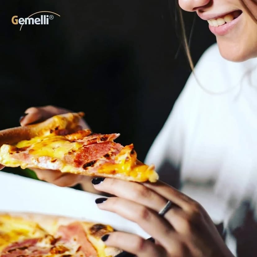 O persoană savurează o felie de pizza cu brânză și mezeluri, într-o imagine promoțională Pizza Gemelli Baia Mare.